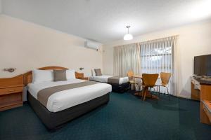 a hotel room with two beds and a television at Pegasus Motor Inn and Serviced Apartments in Brisbane