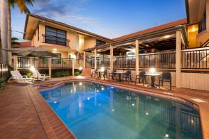 a swimming pool in front of a house at Pegasus Motor Inn and Serviced Apartments in Brisbane