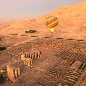 Nile Cruise Luxor & Aswoan Included balloon في الأقصر: بالون هواء ساخن يطير فوق مدينة قديمة