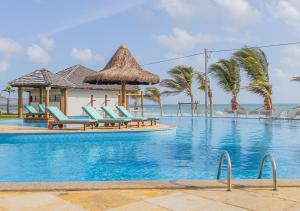 a swimming pool with lounge chairs and the ocean at The Coral Beach Resort by Atlantica in Trairi