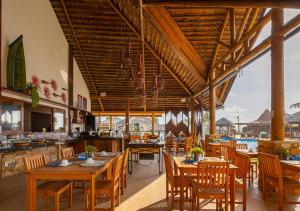 a restaurant with wooden tables and chairs with a view at The Coral Beach Resort by Atlantica in Trairi