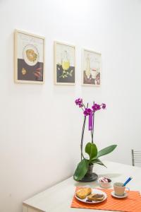 una mesa con un jarrón de flores y cuadros en la pared en La Torre Guest House, en Roma