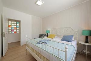 ein Schlafzimmer mit einem weißen Bett mit blauen und gelben Kissen in der Unterkunft Šmuketa in Trogir Haus für 4 Personen in Trogir