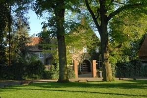 una casa con árboles frente a un patio en Haus Keppelborg: ZI Rosina mit Burggartenblick, en Heek