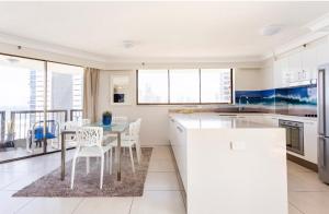 eine Küche mit weißen Schränken sowie einem Tisch und Stühlen in der Unterkunft Spacious & Magnificent Views Apartment in Gold Coast