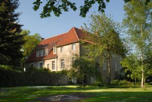 una casa con techo rojo en un patio verde en Haus Keppelborg: ZI Ferdinand mit Rosengartenblick, en Heek