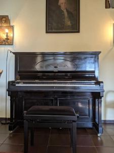 un piano negro con un taburete en una habitación en Haus Keppelborg: ZI Ferdinand mit Rosengartenblick, en Heek