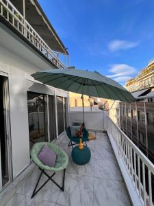 einen Balkon mit einem grünen Sonnenschirm und 2 Stühlen in der Unterkunft Casa de Tres Hermanos in the heart of Athens in Athen