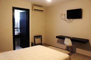 a bedroom with a bed and a desk and a television at Hotel Magnolia in Tampico