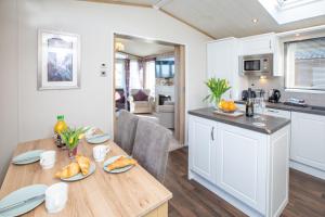 a kitchen and living room with a wooden table with food on it at Nature Haven Hot Tub Lodge 30 Cameron, St Andrews in St. Andrews