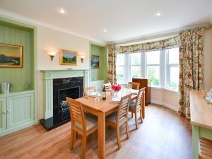 a dining room with a table and chairs and a fireplace at Pinclanty Cottage in Pinmore