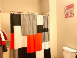 a bathroom with a shower curtain and a toilet at King Size with OSU Theme! in Columbus