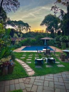 un patio trasero con una piscina con mesa, sillas y sombrilla en Pousada das Brumas en Brumadinho