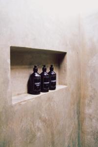 three black bottles sitting on a shelf in a wall at Pousada Casa Marae in Caraíva