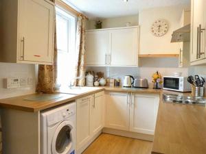 a kitchen with white cabinets and a washing machine at Crinan Canal Cottage in Lochgilphead