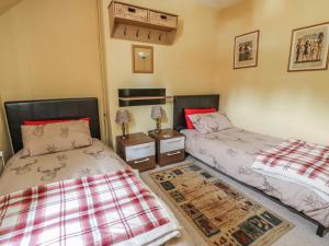 a bedroom with two beds and a rug at Crinan Canal Cottage in Lochgilphead