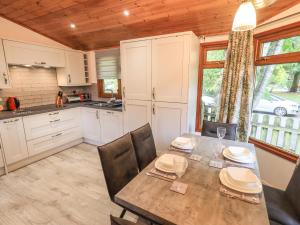 a kitchen with a table and chairs and a kitchen with white cabinets at Cedar Lodge in Windermere