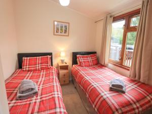 two twin beds in a room with a window at Cedar Lodge in Windermere