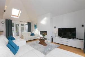 a white living room with a white couch and a tv at Chy Lowen in Carbis Bay