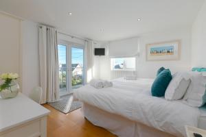 a white bedroom with a large bed and a window at Chy Lowen in Carbis Bay