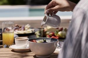 a person pouring food into a bowl on a table at Yria Island Boutique Hotel & Spa in Parasporos
