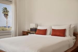 a bedroom with a large white bed with orange pillows at Yria Island Boutique Hotel & Spa in Parasporos