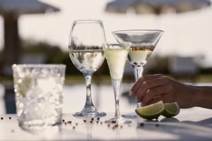 two glasses of white wine and a hand holding a lime at Yria Island Boutique Hotel & Spa in Parasporos