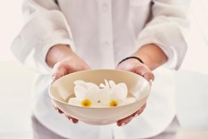 a person holding a white bowl with flowers on it at Yria Island Boutique Hotel & Spa in Parasporos