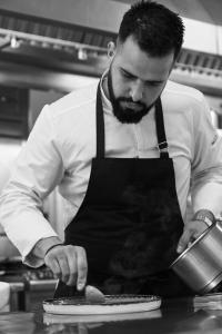 a man wearing an apron preparing food in a kitchen at Yria Island Boutique Hotel & Spa in Parasporos