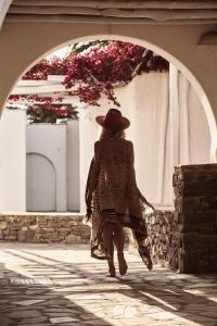 a woman walking down a street under an arch with flowers at Yria Island Boutique Hotel & Spa in Parasporos