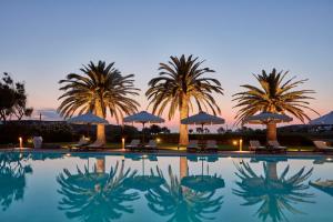 a pool with chairs and umbrellas and palm trees at Yria Island Boutique Hotel & Spa in Parasporos