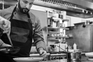 a man in a kitchen preparing food in a bowl at Yria Island Boutique Hotel & Spa in Parasporos