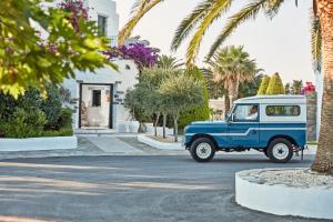 an old blue and white car driving down a street at Yria Island Boutique Hotel & Spa in Parasporos