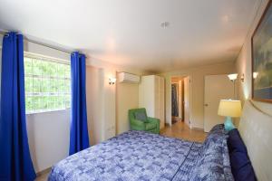 a bedroom with a blue bed and a green chair at 3 min walk from the beach - Blue Waters 25 Apt 3 apts in Bridgetown