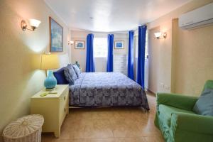 布里奇敦3 min walk from the beach - Blue Waters 25 Apt 3 apts的一间卧室配有一张带蓝色窗帘的床和一张沙发