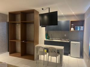 a kitchen with a table and two chairs and a tv at Suítes&Flats MarBello in Maragogi