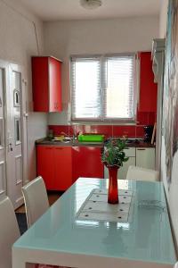 kuchnia z czerwonymi szafkami i stołem z wazonem w obiekcie Apartment Starigrad 11848a w mieście Starigrad-Paklenica