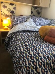 a bed with a black and white comforter and pillows at Albatross at Cleethorpes Pearl in Cleethorpes