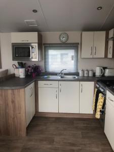 a kitchen with white cabinets and a sink at Albatross at Cleethorpes Pearl in Cleethorpes