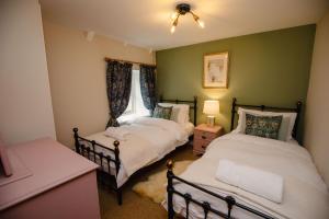 a bedroom with two beds and a window at Keepers Cottage - Rudge Farm Cottages in Bridport
