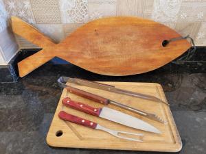 a wooden cutting board with four knives on a cutting board at Casa à beira mar de Maragogi com 3 quartos, 4 banheiros e Área Verde in Maragogi
