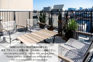 patio z 2 krzesłami i drewnianą ławką na balkonie. w obiekcie GIVE Araiyakushi w Tokio