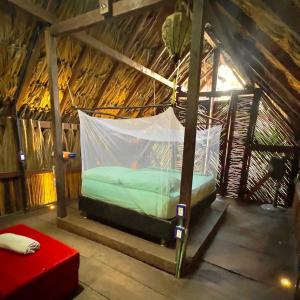 a bed in a room with a hammock in a hut at Kaluta in Palomino