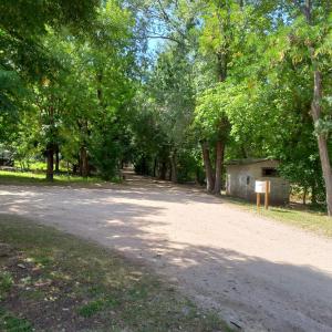 un camino de tierra en un parque con árboles y un edificio en Villa Cura Brochero - La Moradita de VIlla Los Sauces en Villa Cura Brochero