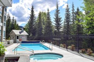 una piscina en un patio trasero con una valla y árboles en Elegant Ski In Ski Out Condo by Harmony Whistler, en Whistler