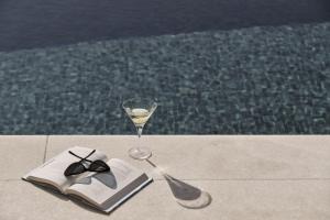 a book and a glass of wine on a table at Yria Island Boutique Hotel & Spa in Parasporos