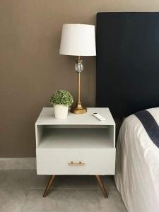 a white nightstand with a lamp and a plant on it at Casa Magnolia 2 in Ciudad Madero