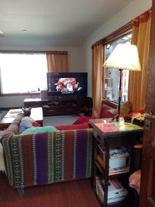een woonkamer met een bank en een televisie bij Bosque Holístico del Fin del Mundo in Ushuaia