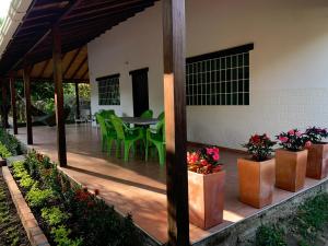 a patio with green chairs and a table with flowers at Hostal Casa Jocolate Minca in Minca