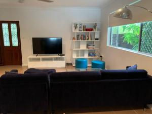 sala de estar con sofá y TV de pantalla plana en Tropical Oasis en Freshwater